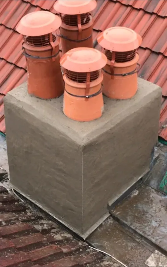 A chimney stack newly rendered by Pro Roofing, with four terracotta pots fitted with cowls and lead flashing around the base