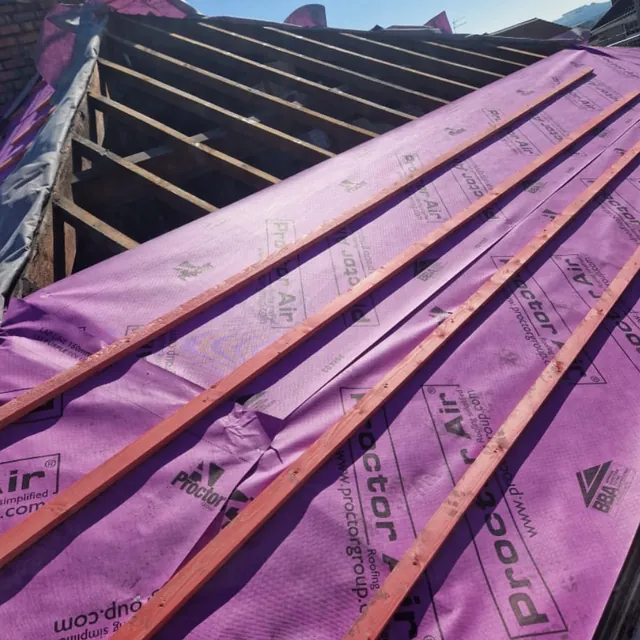 Stage two of the re-roof: new pink breathable membrane and battens going on, with bare rafters further along