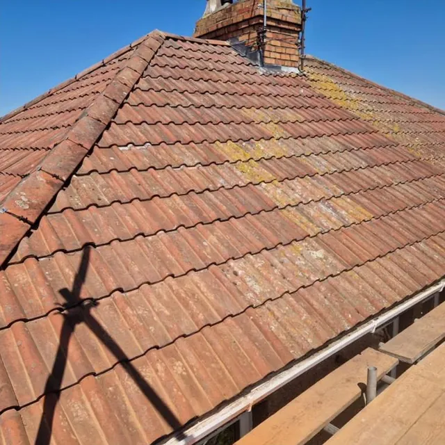 Clay double Roman tiles and mortar-bedded hip tiles on a hipped roof re-covered by Pro Roofing, seen from the scaffold